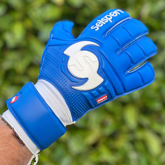 Blue Selsport Goalkeeper glove with a logo on a blurred green background