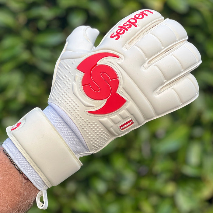 Selsport white goalkeeper glove with red logo on a blurred green background