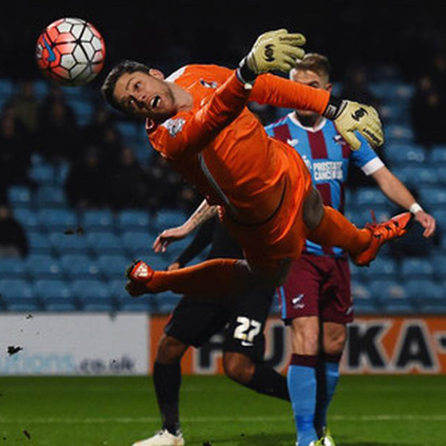 Luke Daniels goalkeeper in Scunthorpe Kit at full stretch across the goal making a save in Selsport Wrappa Classic goalkeeper gloves