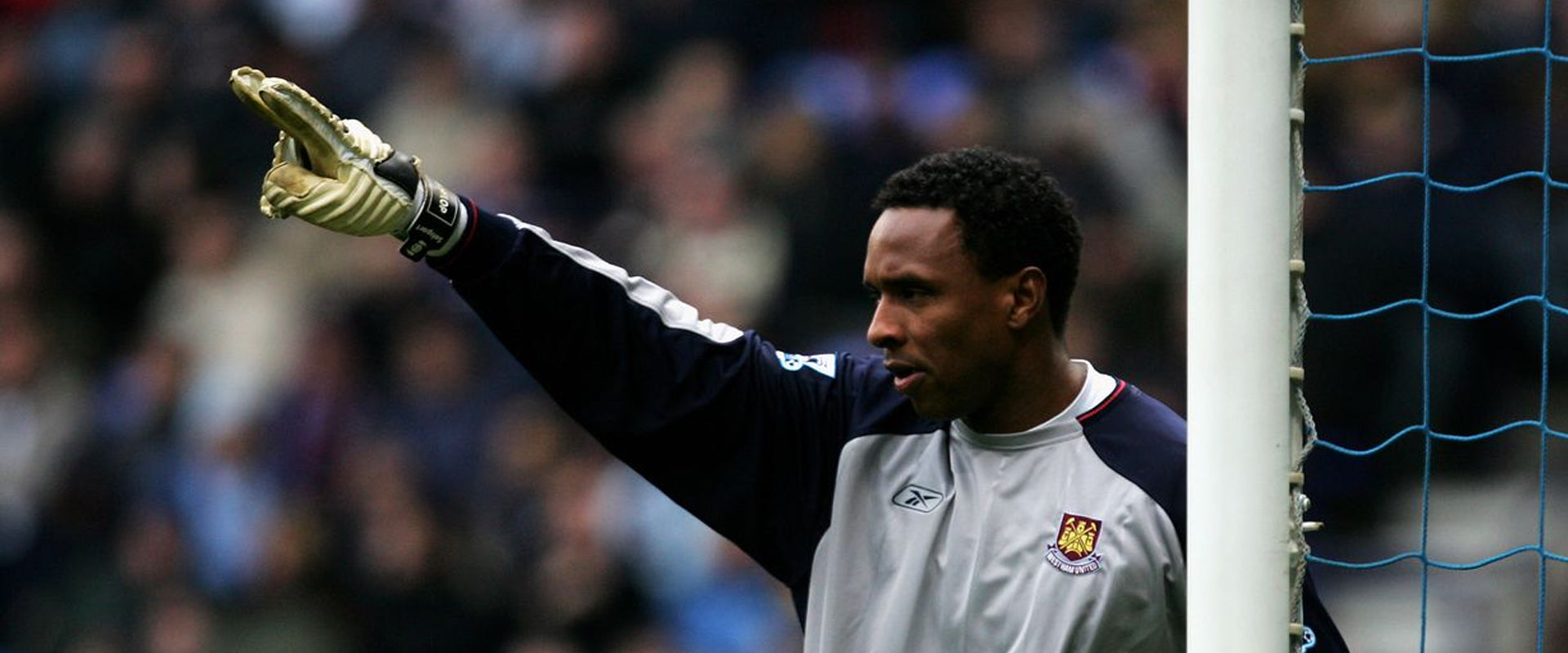 Shaka Hislop in West ham goalkeeper shirt standing in goal pointing his right arm in front of him wearing Selsport goalkeeper gloves