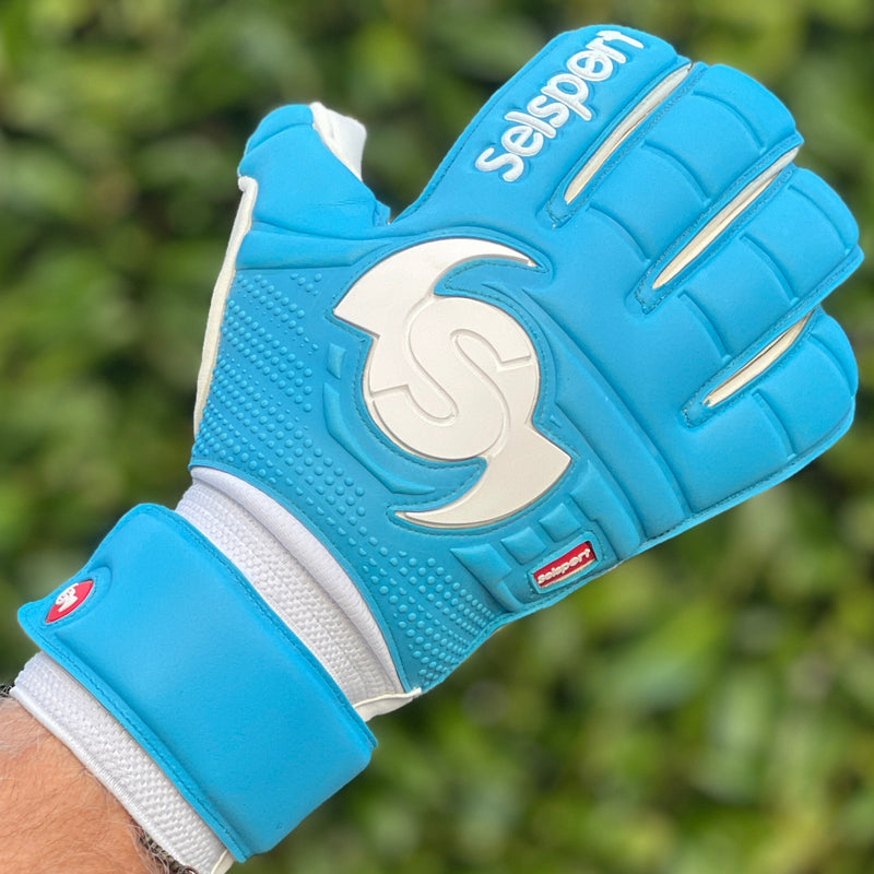Cyan Selsport goalkeeper glove with a brand logo on a blurred green background