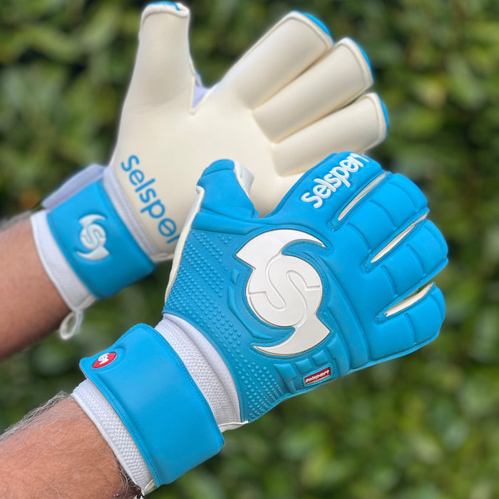 Cyan Selsport goalkeeper gloves with a visible brand logo on a blurred green background