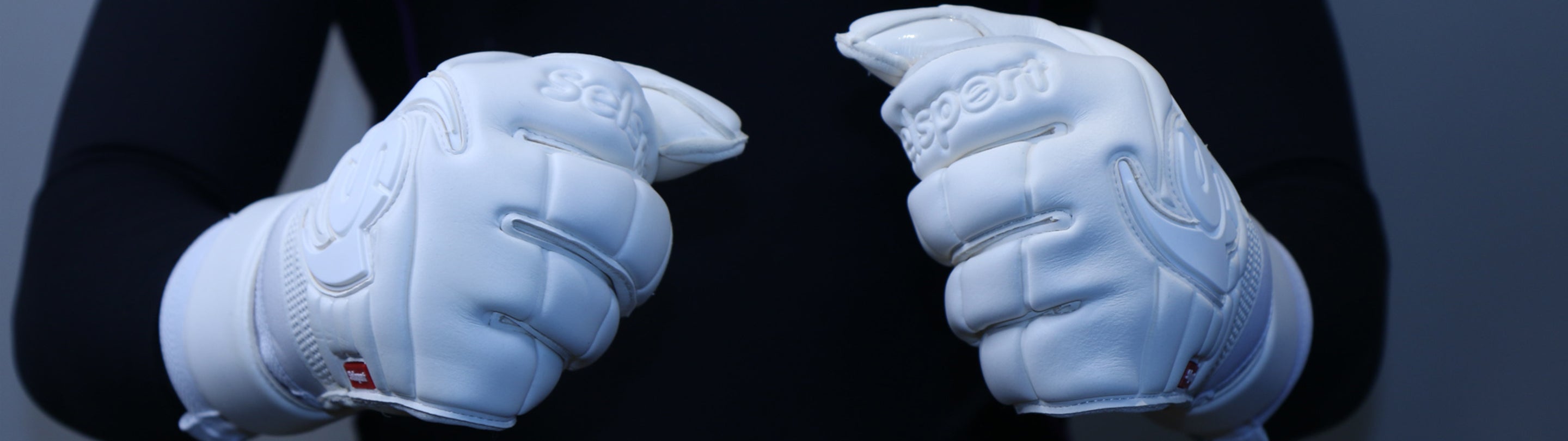 Pair of hands with Selsport Wrappa Phantom white goalkeeper gloves made into fists