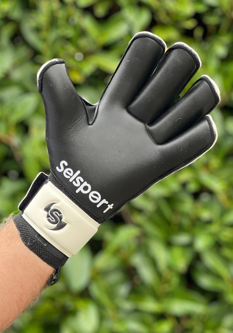 Selsport white & Black goalkeeper  glove with  branded logo on a blurred green background