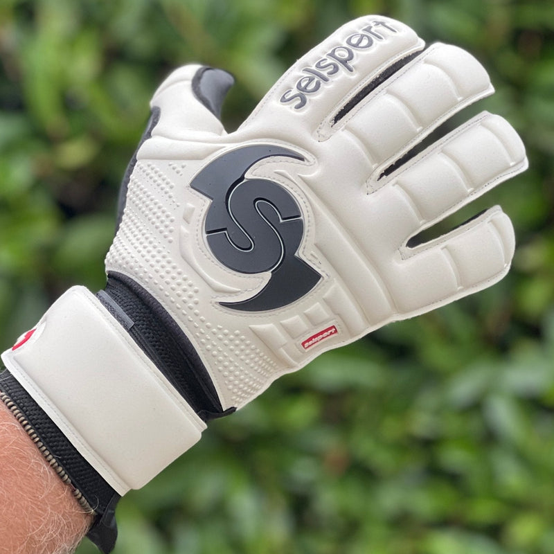 Selsport white & Black goalkeeper  glove with  branded logo on a blurred green background