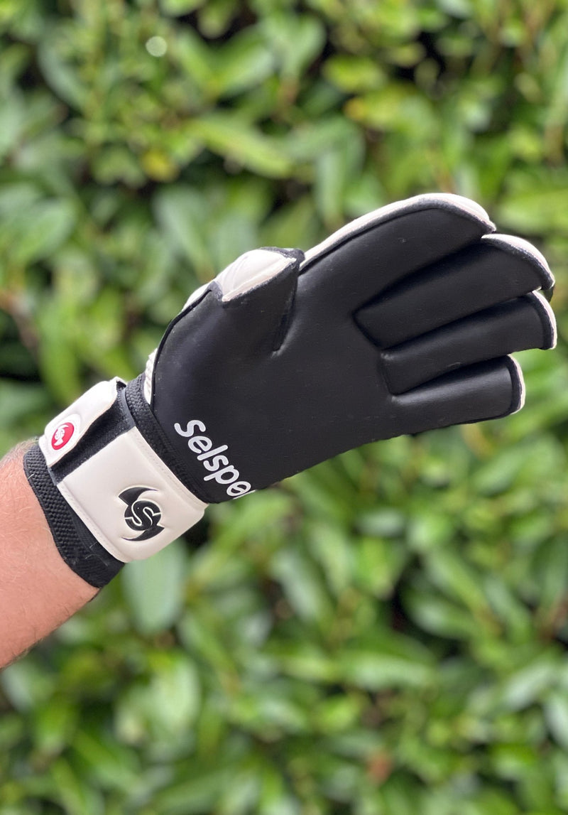 Selsport white & Black goalkeeper  glove with  branded logo on a blurred green background
