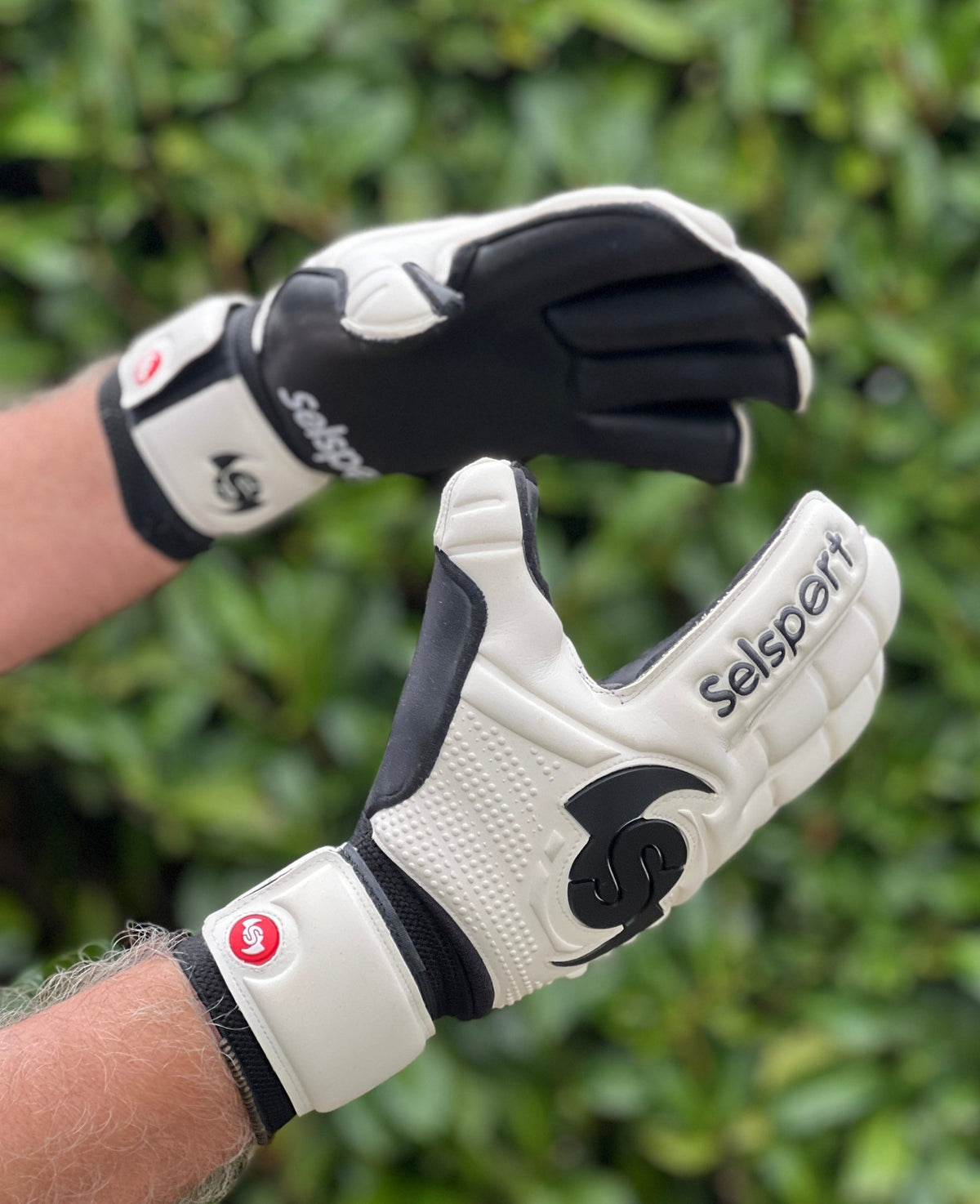 Selsport white & Black goalkeeper  gloves with  branded logo on a blurred green background