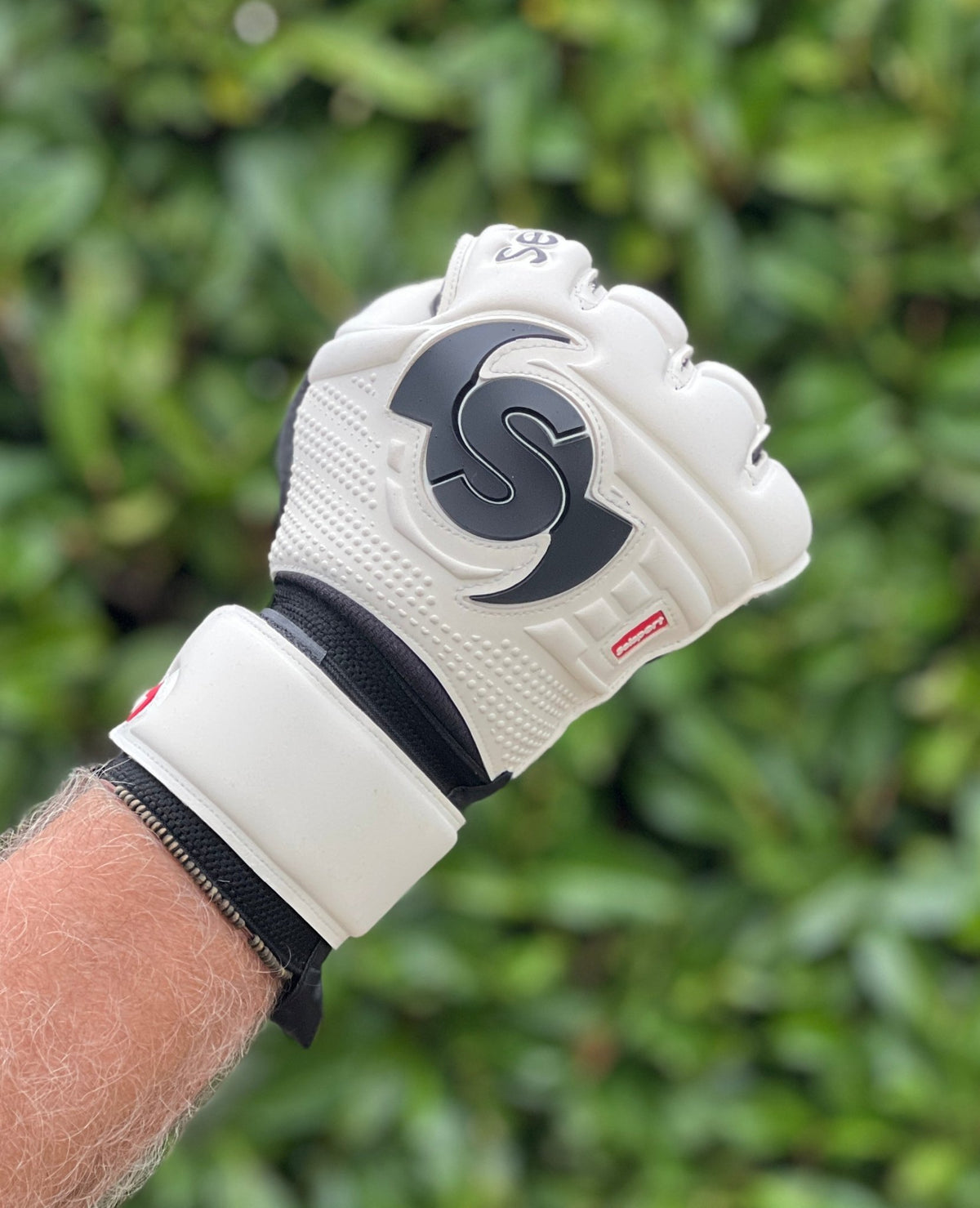 Selsport white & Black goalkeeper  glove with  branded logo on a blurred green background