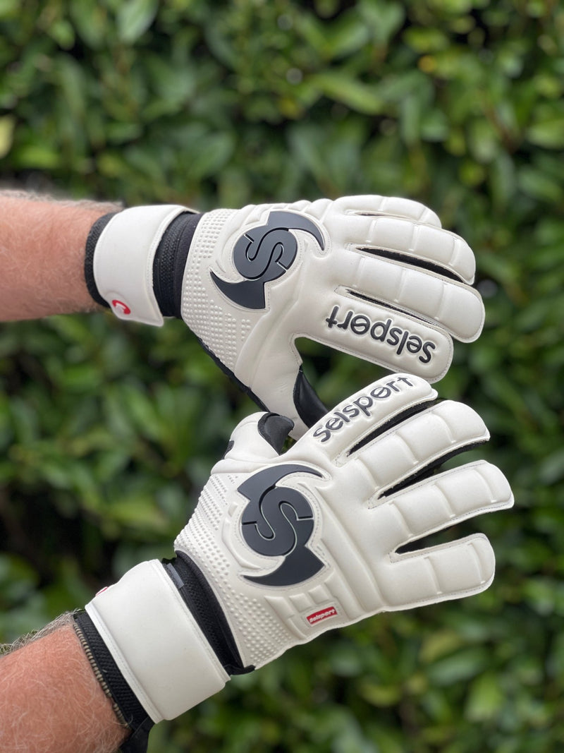 Selsport white & Black goalkeeper  gloves with  branded logo on a blurred green background
