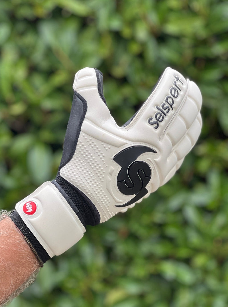 Selsport white & Black goalkeeper  glove with  branded logo on a blurred green background