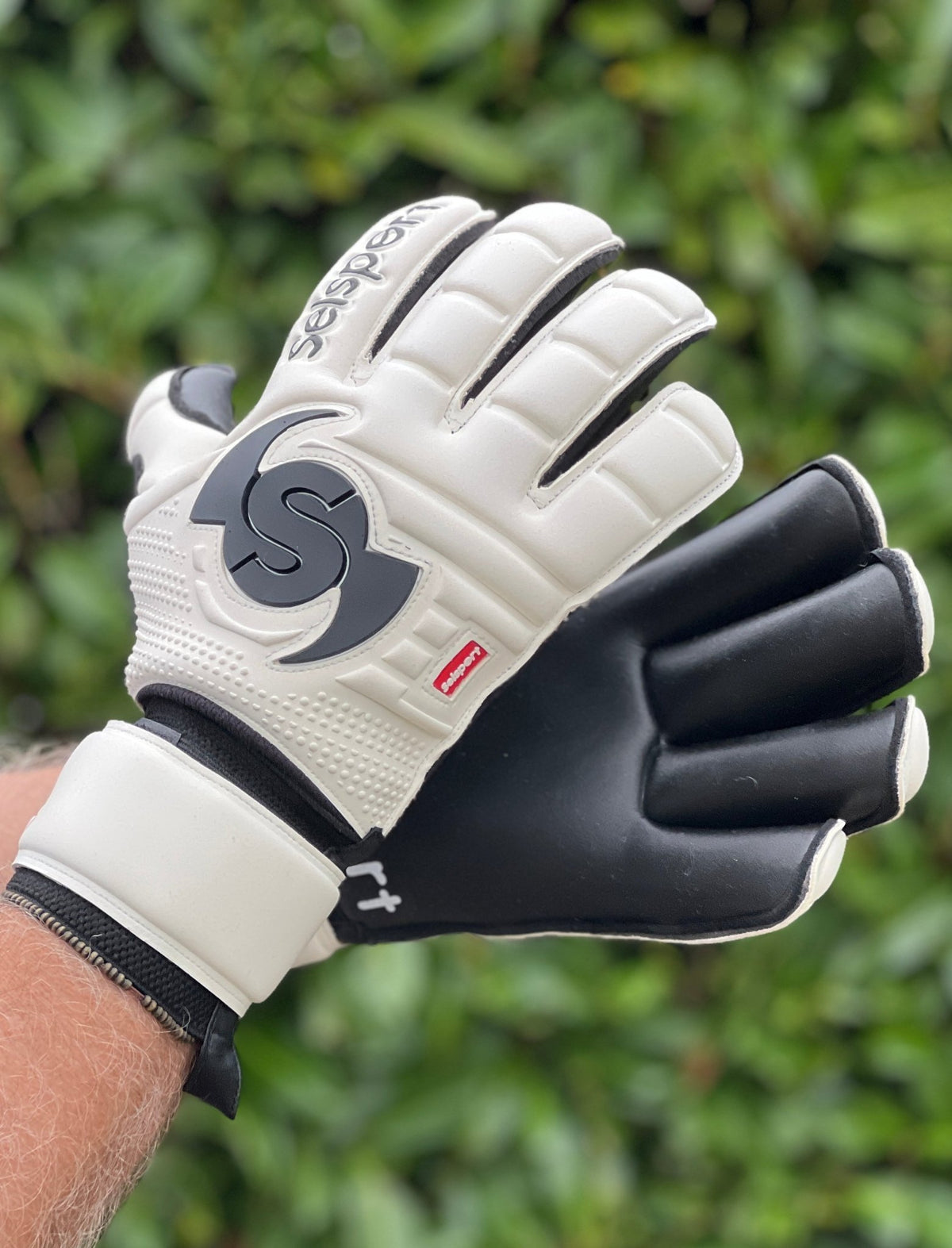 Selsport white & Black goalkeeper  gloves with  branded logo on a blurred green background