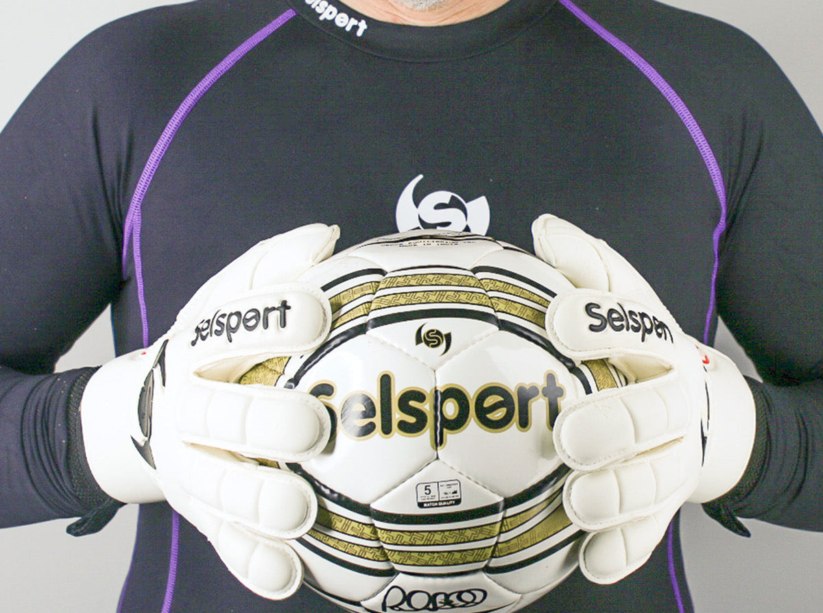 Selsport Ultimate UA+ Wrappa classic hybrid flat palm cut goalkeeper glove backhand with s wing logo both hands holding a football